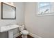 Powder room features a pedestal sink, toilet, and window with natural light at 214 Leland Way, Woodstock, GA 30188