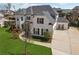 Beautiful two-story home featuring white brick, black shutters, mature trees, and professional landscaping at 214 Leland Way, Woodstock, GA 30188