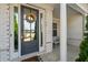 Covered front porch with a wreath hanging on the door, stone pillars, and a rocking chair at 214 Leland Way, Woodstock, GA 30188