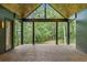Covered back porch with wood flooring and soaring ceiling with views of a lush green backyard at 402 Chattahoochee St, Roswell, GA 30075