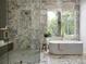 Stunning bathroom features marble walls, a spacious shower, and a luxurious soaking tub by a window at 402 Chattahoochee St, Roswell, GA 30075