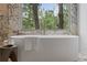 Luxurious bathroom featuring a modern soaking tub with beautiful marble accents and serene wooded views at 402 Chattahoochee St, Roswell, GA 30075