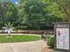 Town center featuring a modern art sculpture, event postings, and seating area surrounded by lush landscaping at 402 Chattahoochee St, Roswell, GA 30075