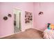 Comfortable pink bedroom with decorative shelf and doorway to the neighboring room at 3341 Camelot Way, Loganville, GA 30052