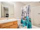 Well-lit bathroom with a tub/shower, floral shower curtain, and a wooden vanity at 3956 Church View Ln, Suwanee, GA 30024