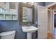 Bathroom with a white pedestal sink, framed mirror, and additional storage with overhead cabinet and white baskets at 4361 Stanley Dr, Powder Springs, GA 30127