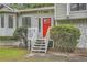 Close-up of a house with a stone foundation and a bright red door with decorative bushes at 1945 Chateau Ln, Lithia Springs, GA 30122