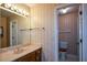 Neutral wallpaper adorns the walls of this bathroom with a vanity and a commode at 154 Weatherly Way, Alpharetta, GA 30009