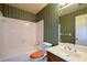 This bathroom has a tub/shower combo, commode, vanity, mirror, and green-print wallpaper at 154 Weatherly Way, Alpharetta, GA 30009