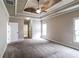 Main bedroom features a tray ceiling, ceiling fan, neutral carpet and multiple windows at 1209 Richmond Rdg, Loganville, GA 30052