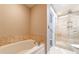 This primary bath features a soaking tub and glass-enclosed shower with travertine tile at 2626 Peachtree Nw Rd # 412, Atlanta, GA 30305