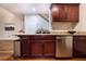 Kitchenette with dark wood cabinets, granite counters, stainless dishwasher, wooden floors, and a trash can at 2626 Peachtree Nw Rd # 412, Atlanta, GA 30305