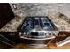 Close up of a stainless steel gas stove with granite countertops and gray brick backsplash at 2626 Peachtree Nw Rd # 412, Atlanta, GA 30305