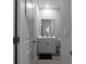 A modern half bath with a gray vanity, stylish mirror, and wood-look tile flooring at 4171 Dean Grove Way, Loganville, GA 30052
