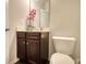 Powder room features toilet, single sink vanity with dark wood cabinets, and neutral colored walls at 164 Madison Grace Ave, Mcdonough, GA 30252