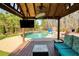 Covered poolside patio boasts outdoor seating, a mounted television, and stone fireplace at 5960 Sarah Orr Ln, Cumming, GA 30040
