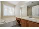 Bright bathroom featuring a soaking tub, vanity with storage, and large mirror at 792 Russell Dr, Riverdale, GA 30296