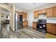 Well-lit kitchen features stainless steel appliances, wood cabinets, and gray wood-look flooring at 792 Russell Dr, Riverdale, GA 30296