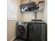 A modern laundry room showcasing a gray front-load washer and dryer with convenient shelving above at 792 Russell Dr, Riverdale, GA 30296