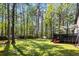 Lush backyard with tall trees, play equipment, a black deck, and a grassy area perfect for outdoor activities at 2425 Shiloh Sw Dr, Marietta, GA 30064