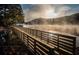 Beautiful lake view at sunrise featuring a wooden bridge with early morning fog and trees lining the bank at 250 Martin Ridge Ct, Roswell, GA 30076
