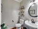 Chic powder room with a vessel sink, round mirror, and decorative floating shelves at 3642 Falls Trl, Winston, GA 30187