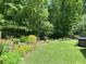 Large landscaped backyard with flower beds, green grass and wooded area at 3455 Buffington Ln, Cumming, GA 30040