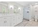 Bright bathroom featuring double sinks, a glass door shower, tile floors, and white cabinets at 995 Litchfield Pl, Roswell, GA 30076