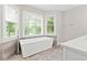 Luxurious bathroom featuring a soaking tub with a modern faucet, tile floors, and natural light at 995 Litchfield Pl, Roswell, GA 30076