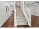 Interior view of staircase featuring wood floors, white railing, and access to the kitchen at 995 Litchfield Pl, Roswell, GA 30076