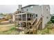 Exterior shot of the back of the home, featuring a screened in porch and wooden staircase to the backyard at 6675 Flagstone Ct, Cumming, GA 30028