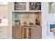 Custom bar area with wine fridge, stone backsplash, upper storage for glassware and wine bottles, and a sink at 2940 W Village Dr # 60, Suwanee, GA 30024