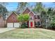 Elegant brick home with a well-manicured lawn, two-car garage, and vibrant red door at 10460 Cranchester Way, Alpharetta, GA 30022