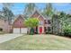 Charming two-story brick home with a manicured lawn, complemented by a vibrant red front door and a two-car garage at 10460 Cranchester Way, Alpharetta, GA 30022
