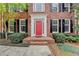 Up-close view of the brick facade highlighting the striking red front door and neat landscaping of the property at 10460 Cranchester Way, Alpharetta, GA 30022