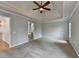 Large main bedroom featuring carpet, ceiling fan, tray ceilings, bathroom entrance, and neutral paint at 10460 Cranchester Way, Alpharetta, GA 30022