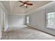 Spacious main bedroom featuring carpet, ceiling fan, tray ceilings, and neutral paint at 10460 Cranchester Way, Alpharetta, GA 30022