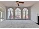 Bright living room with three large windows overlooking a deck, ceiling fan, and neutral carpet at 1924 Wilkenson Xing, Marietta, GA 30066