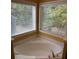 Bathroom featuring a corner tub and large windows with lush outdoor views at 1112 Gather Dr, Lawrenceville, GA 30043