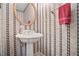 Cozy half-bathroom featuring striped wallpaper, pedestal sink and gold oval mirror at 4093 Tritt Homestead Dr, Marietta, GA 30062