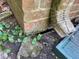 Close-up of the base of the brick home's exterior with a drain spout, cement, and vegetation around it at 1511 Stonewood Dr, Norcross, GA 30093