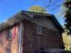 Side view of brick home, with red shutters and overgrown landscaping, showing the architectural details at 1511 Stonewood Dr, Norcross, GA 30093