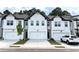 New townhomes with a modern farmhouse exterior feature two-car garages and ample parking at 421 Auburn Valley Way, Auburn, GA 30011