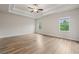 Serene main bedroom featuring hardwood floors, tray ceiling, ceiling fan, and ample natural light at 4229 Brookmont Way, Auburn, GA 30011