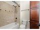 Well-lit bathroom featuring a bathtub with tile surround, a toilet, and a dark wood cabinet at 2875 Waterstone Dr, Cumming, GA 30041