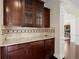 Butler pantry with dark wood cabinets, granite countertops, and decorative tile backsplash at 2875 Waterstone Dr, Cumming, GA 30041