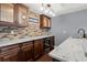 An elegant wet bar area featuring stone accents, wooden cabinets, wine cooler and granite countertops at 2875 Waterstone Dr, Cumming, GA 30041
