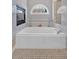 A luxurious soaking tub with tile surround, decorative window, and stylish fixtures for a relaxing bath experience at 3509 Ivy Manor Se Rd, Smyrna, GA 30080