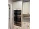 Stainless steel appliances complement white cabinets, granite counters, and green decorative knobs at 4748 Arcado Sw Rd, Lilburn, GA 30047