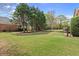 Lush green backyard with mature trees and outdoor fireplace and kitchen at 1060 Meadow Brook Dr, Woodstock, GA 30188